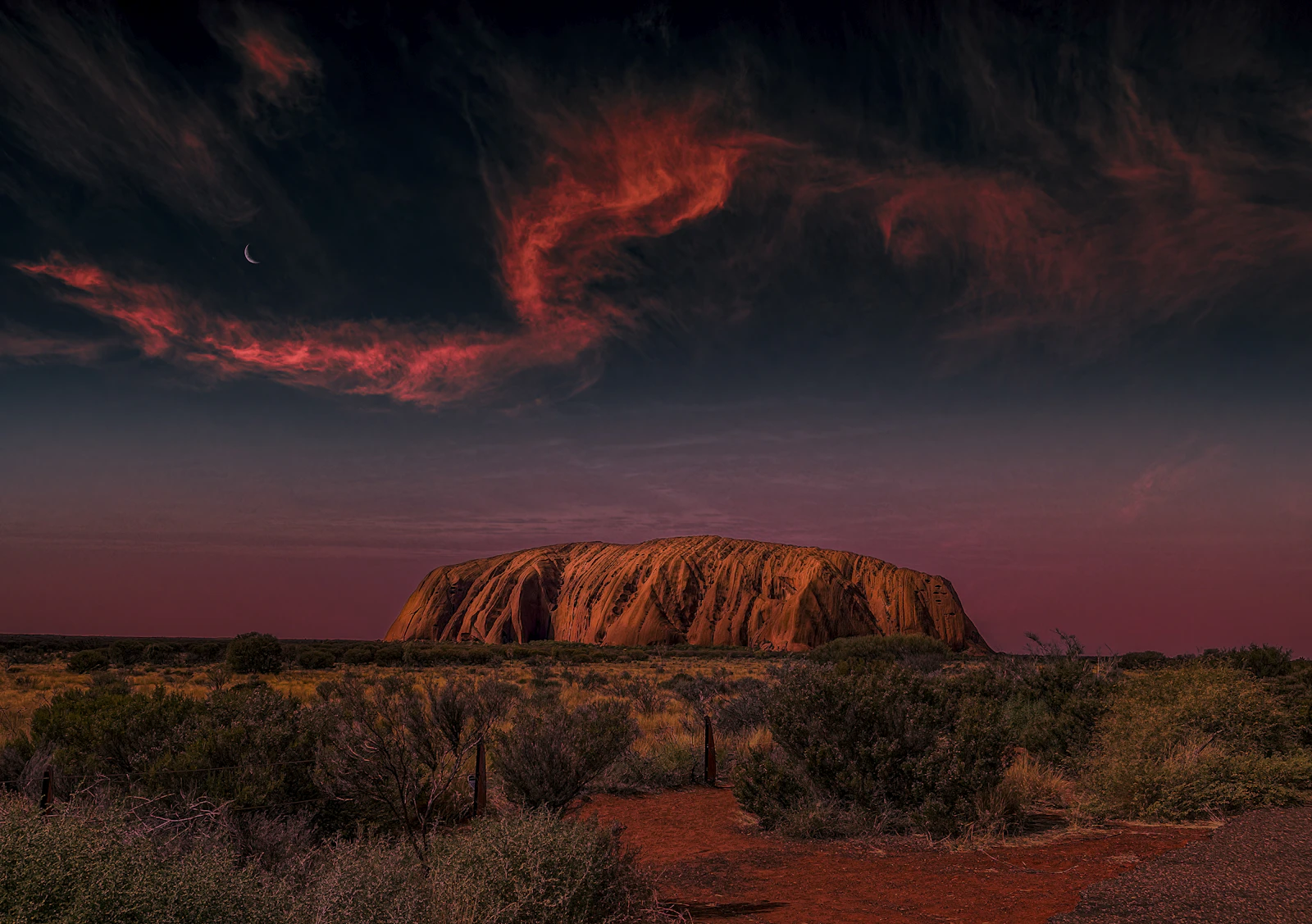 El monolito rojo de Uluru al atardecer sobre la llanura del desierto australiano