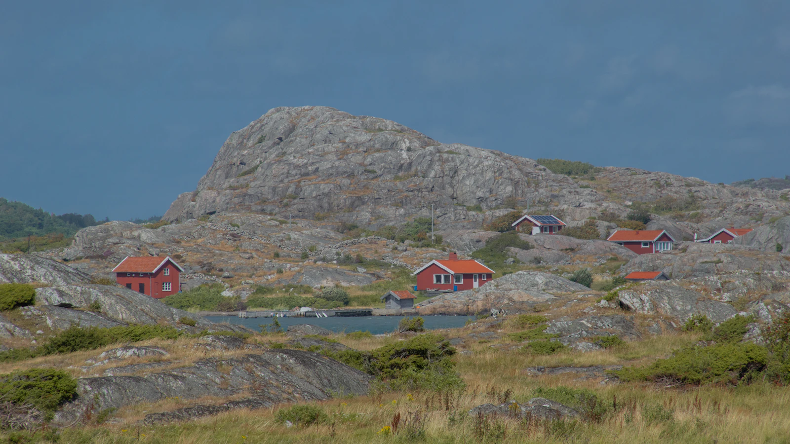 Rocas de granito pulidas y casas rojas junto al mar en la costa de Bohuslän